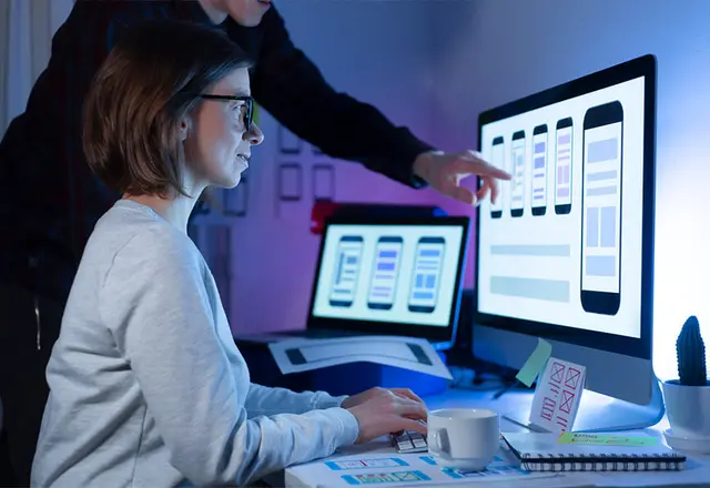 Software developers collaborating on project at desktop computer