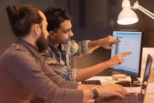 Two professionals collaborating on a desktop computer while discussing technology strategy, representing CTO outsourcing and leadership in software development.