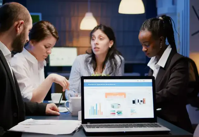 Healthcare professionals collaborating over a laptop with charts, discussing interoperability and data sharing.