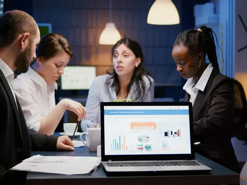 Healthcare professionals collaborating over a laptop with charts, discussing interoperability and data sharing.